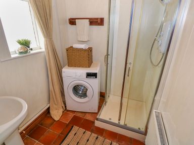A bathroom with a washing machine shower enclosure window with curtains and a sink at Aggrafard in Oughterard County Galway