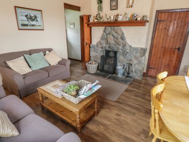 A living room with a stone fireplace a wooden coffee table two sofas and a wooden dining table with chairs at Corrib near Oughterard County Galway