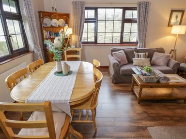 A dining area with wooden table and chairs next to a living room with sofa and coffee table at Corrib Near Oughterard County Galway