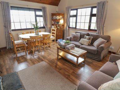 A living room with sofas a coffee table a dining table with chairs and a wooden cabinet at Corrib Near Oughterard County Galway