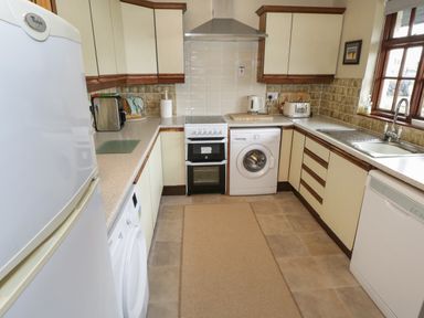 A kitchen with white appliances including refrigerator, washing machine, oven, kettle, toaster, and dishwasher near a window at Corrib Near Oughterard County Galway