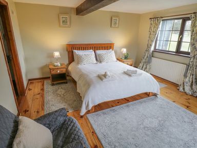 A bedroom with a wooden bed and two bedside tables with lamps near a window with curtains at Corrib Near Oughterard County Galway