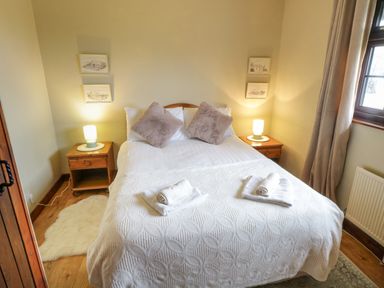A bedroom with a double bed two bedside tables with lamps and windows with curtains at Corrib Near Oughterard County Galway