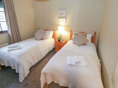 A bedroom with two single beds side by side separated by a wooden nightstand with a lamp at Corrib Near Oughterard County Galway