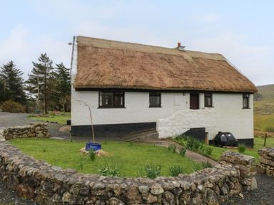 A small house with a thatched roof and white walls surrounded by a stone wall at Corrib Near Oughterard County Galway