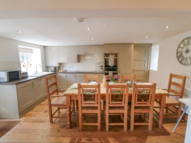 A kitchen with wooden dining table and chairs and built in cabinets at Tillers Cottage in Ebberston