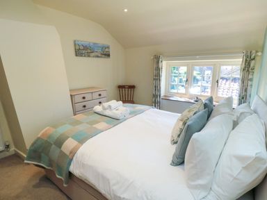 A bedroom with a bed folded towels chest of drawers and window with curtains at Tillers Cottage in Ebberston
