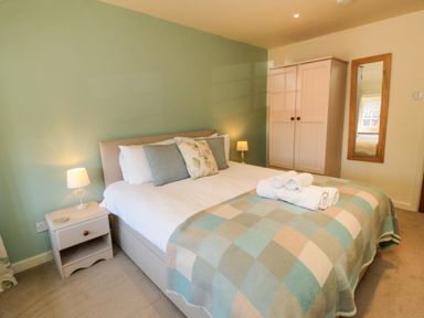 A bedroom with a bed nightstands wardrobe and mirror at Tillers Cottage in Ebberston