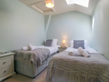 A bedroom with two single beds a bedside table lamp and rolled towels at Tillers Cottage in Ebberston