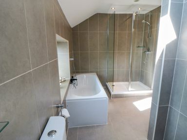 A bathroom with a bathtub shower enclosure and toilet at Tillers Cottage in Ebberston