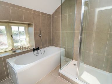 A bathroom with a bathtub and a separate shower enclosure at Tillers Cottage in Ebberston