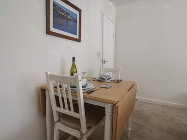 A dining area with a wooden table set for two and white chairs at 16 Church Street in Lyme Regis