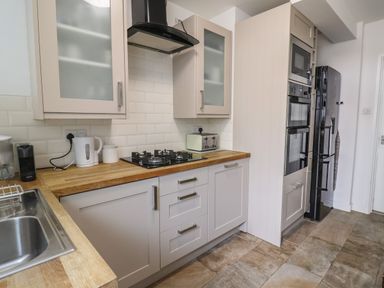 A kitchen with a gas stove oven microwave refrigerator kettle toaster and sink at 16 Church Street in Lyme Regis