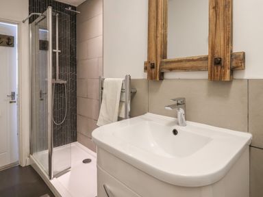 A bathroom with a shower, sink, towel rack, and wooden framed mirror at 16 Church Street in Lyme Regis