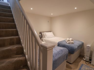A small bedroom with two single beds next to a staircase at 16 Church Street in Lyme Regis