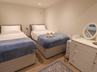 A bedroom with two single beds a bedside table with a lamp a chest of drawers with a round mirror and carpet at 16 Church Street in Lyme Regis