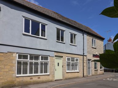 A street view of a two-story building with windows and doors at 16 Church Street Lyme Regis
