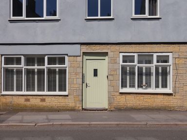 Exterior of a building with a light green door and white windows with shutters at 16 Church Street in Lyme Regis