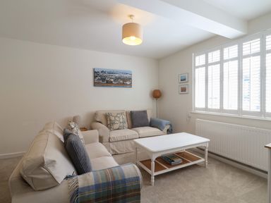 A living room with two sofas a coffee table a floor lamp and window shutters at 16 Church Street Lyme Regis