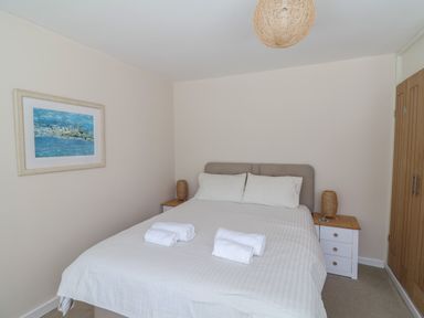 A bedroom with a bed and white sheets with rolled towels on the bed at 16 Church Street in Lyme Regis