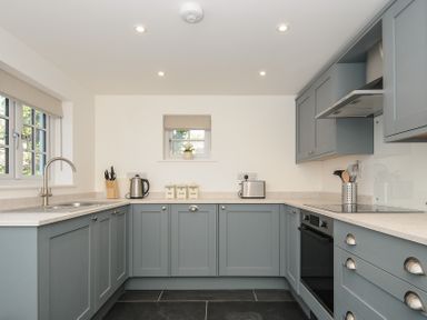 A kitchen with blue cabinets appliances and windows at Sunrise Cottage in St Kew Highway near Wadebridge