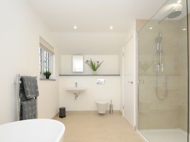 A bathroom with a shower area sink toilet towel rack window and small plant at Sunrise Cottage in St Kew Highway near Wadebridge