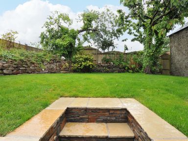 A garden with grass and a stone wall at Sunrise Cottage St Kew Highway near Wadebridge