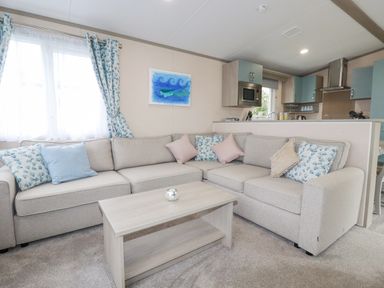 A living room with a sectional sofa and coffee table next to a kitchen at The Mermaid A04 in Par