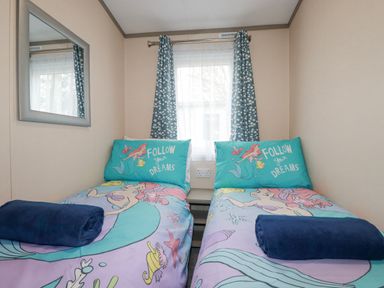 A bedroom with two single beds with The Little Mermaid bedding and blue rolled towels at The Mermaid A04 in Par