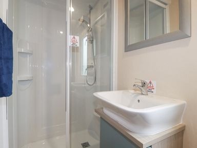A bathroom with a shower enclosure and a sink with a mirror above at The Mermaid A04 in Par