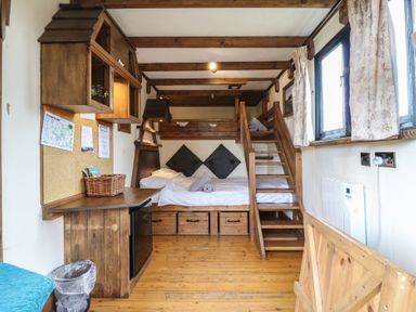 A small room with wooden bunk beds a wooden desk a mini fridge and two windows with curtains at Daisy Cow Shed 1 in Easton near Campsea Ashe