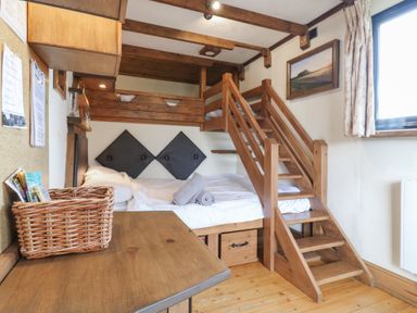 A bedroom with a wooden bunk bed a wooden desk a wicker basket and a window at Daisy Cow Shed 1 Easton near Campsea Ashe