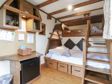 A bedroom with wooden bunk beds a desk with a refrigerator and a cork bulletin board at Daisy Cow Shed 1 Easton near Campsea Ashe