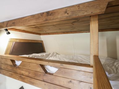 A wooden bunk bed with white bedding and a small wall light at Daisy Cow Shed 1 in Easton near Campsea Ashe
