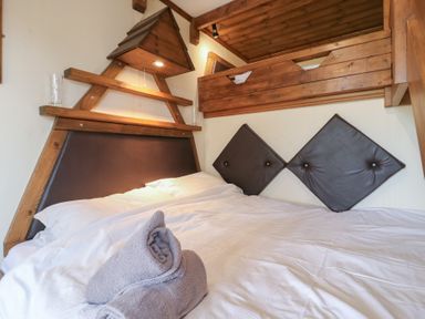 A bedroom with a wooden bunk bed white bedding and folded towels on the bed at Daisy Cow Shed 1 Easton near Campsea Ashe