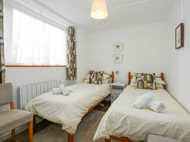 A bedroom with two single beds a chair and a bedside table at Ael Y Don in Llandanwg