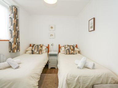 A bedroom with two single beds with patterned cushions and towels on them at Ael Y Don in Llandanwg
