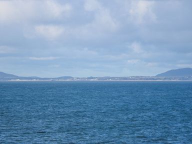 An ocean view with distant land and hills under a cloudy sky at Ael Y Don in Llandanwg