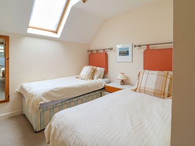 A bedroom with two single beds with orange headboards and a skylight window at 50 Fernhill Heights in Charmouth