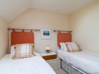A bedroom with two single beds a nightstand and a lamp at 50 Fernhill Heights in Charmouth