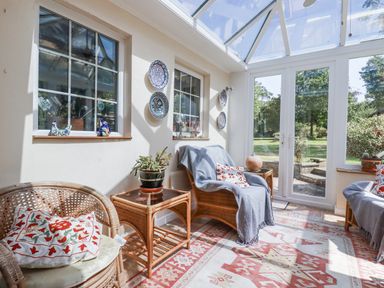 A conservatory with a sofa and plants at Temple House Goonhavern