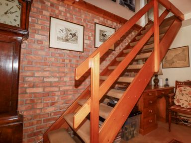 A staircase with wooden railing and wall art at Temple House in Goonhavern