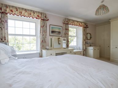 A bedroom with a bed and two windows at Temple House in Goonhavern