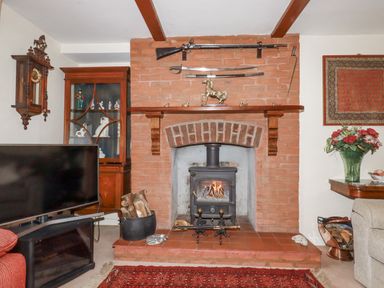 A living room featuring a fireplace with a stove and wood at Temple House in Goonhavern