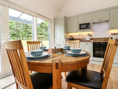 A kitchen with a round wooden dining table set for four people with plates bowls wine glasses and wooden chairs at Strawberry Cottage Wester Essendy near Dunkeld