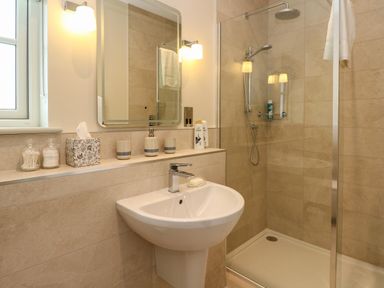 A bathroom with a sink mirror and shower at Strawberry Cottage in Wester Essendy near Dunkeld