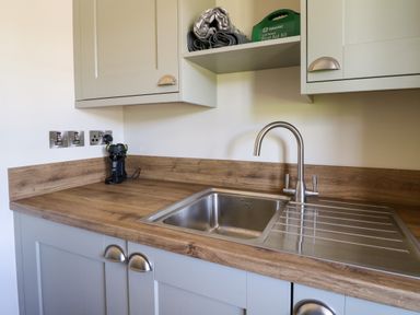 A kitchen sink area with wooden countertops cabinets and a first aid kit on a shelf at Bramble Cottage Wester Essendy near Dunkeld