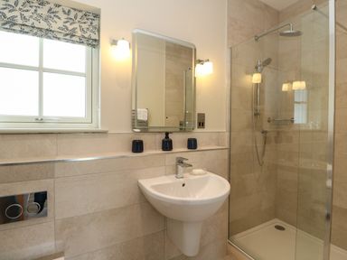 A bathroom with a shower area sink mirror and a window at Bramble Cottage Wester Essendy near Dunkeld