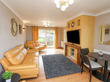 A living room with leather sofas a wall-mounted television and a dining table at 315 Filey Road in Scarborough