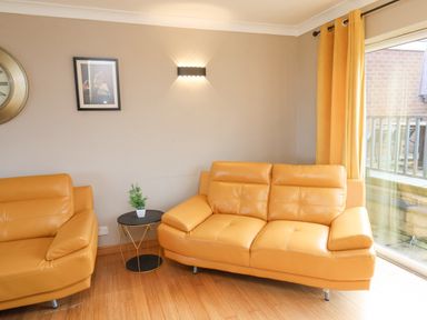 A living room with two yellow leather sofas a small round table with a plant and yellow curtains at 315 Filey Road in Scarborough